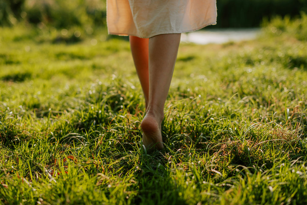 Mujer caminando descalza en un prado de hierba